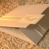 Silver folded wedding inviation with cream and silver ribbon detail